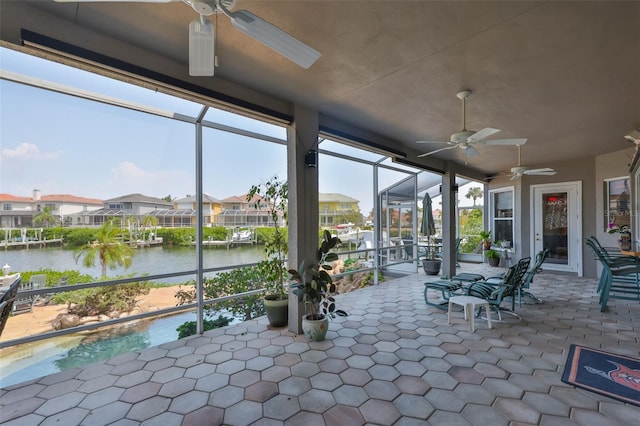 view of patio with ceiling fan, a water view, a lanai, and a residential view
