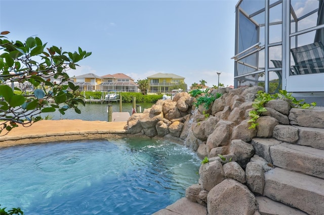 view of pool with a boat dock, glass enclosure, a water view, and a residential view