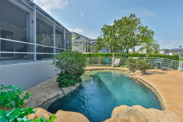 view of swimming pool featuring fence and glass enclosure