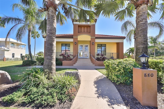 view of front of home featuring french doors, a tile roof, stucco siding, and a porch