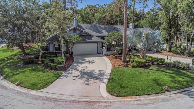 view of front of property featuring concrete driveway, a front yard, a chimney, and a garage