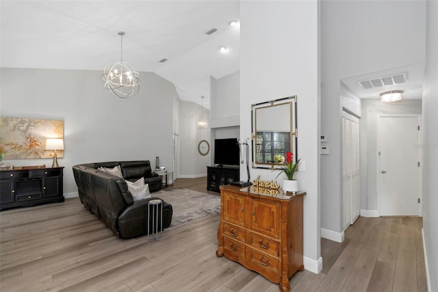 living room with light wood-style floors, a chandelier, high vaulted ceiling, and baseboards