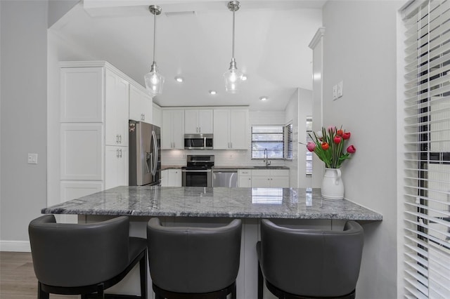 kitchen featuring stainless steel appliances, a sink, white cabinetry, a peninsula, and recessed lighting