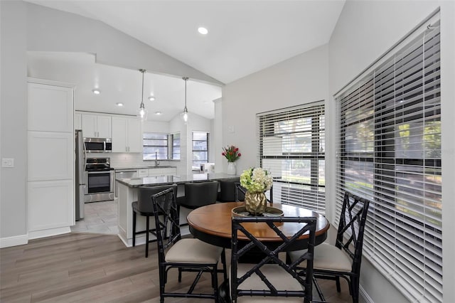 dining room featuring light wood-type flooring, recessed lighting, and high vaulted ceiling