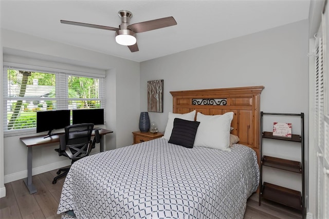 bedroom featuring wood finished floors, baseboards, an office area, and ceiling fan