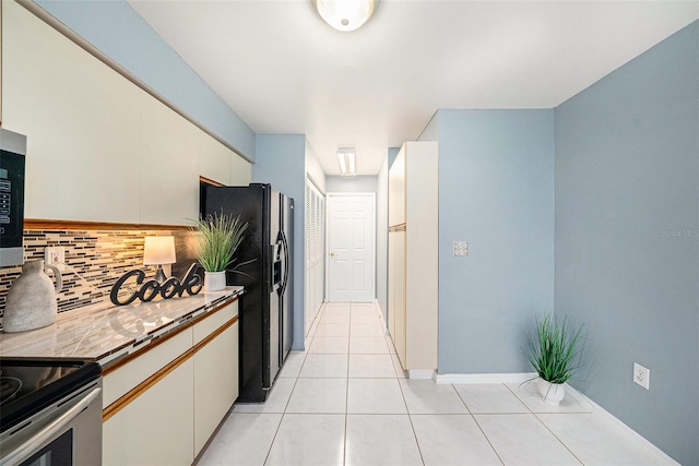 4270 Boston Cir, New Port Richey, FL 34653 - kitchen with decorative backsplash, black fridge, light tile patterned floors, light countertops, and baseboards