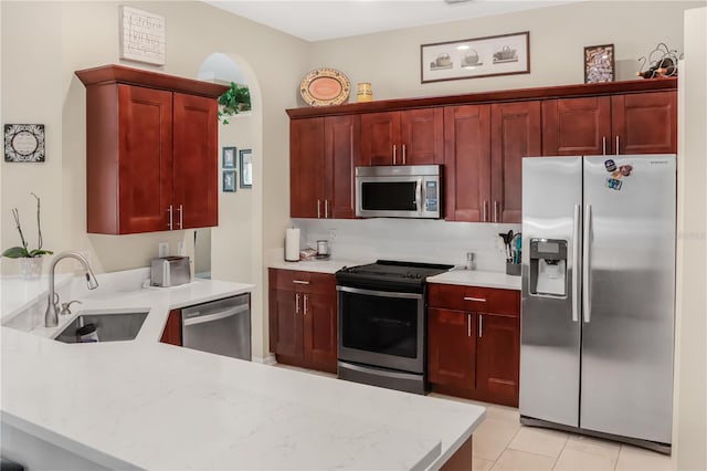 7533 Dunbridge Dr, Odessa, FL 33556 - kitchen with appliances with stainless steel finishes, a sink, a peninsula, dark brown cabinets, and light tile patterned floors