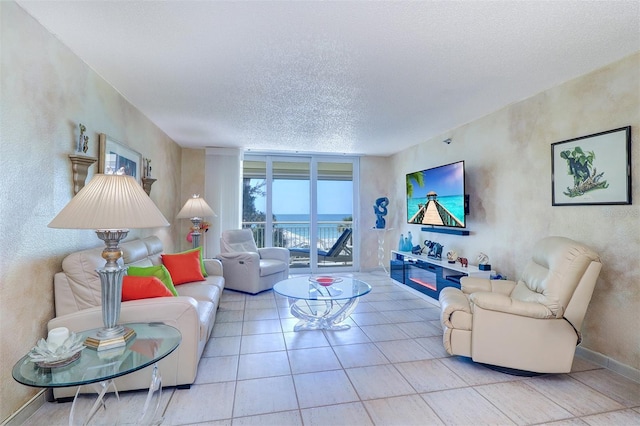 2504 Gulf Blvd Unit 201, Indian Rocks Beach, FL 33785 - living room featuring a textured ceiling, a wall of windows, a textured wall, baseboards, and tile patterned flooring
