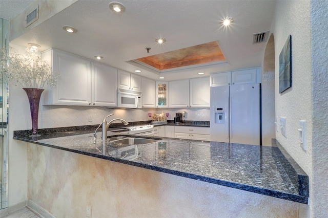 2504 Gulf Blvd Unit 201, Indian Rocks Beach, FL 33785 - kitchen with white appliances, a peninsula, a sink, a raised ceiling, and dark stone counters