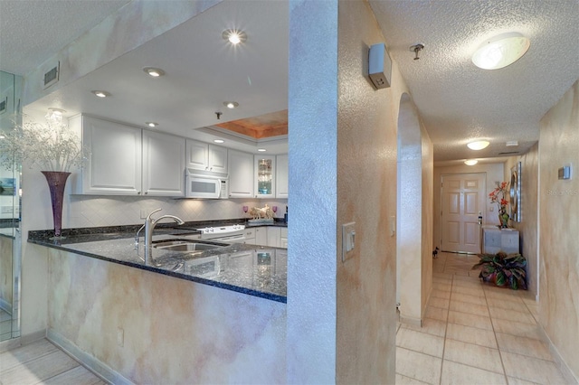 2504 Gulf Blvd Unit 201, Indian Rocks Beach, FL 33785 - kitchen featuring white appliances, a textured ceiling, dark stone countertops, a textured wall, and white cabinets