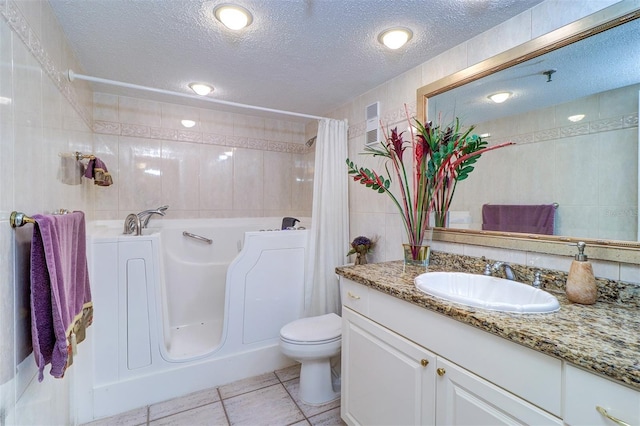 2504 Gulf Blvd Unit 201, Indian Rocks Beach, FL 33785 - bathroom featuring tile walls, a textured ceiling, a tub to relax in, vanity, and toilet