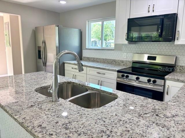 6952 W Barbara Ann Ln, Homosassa, FL 34446 - kitchen with appliances with stainless steel finishes, a sink, white cabinetry, tasteful backsplash, and recessed lighting