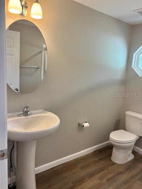 6952 W Barbara Ann Ln, Homosassa, FL 34446 - half bathroom featuring toilet, wood finished floors, baseboards, and a sink