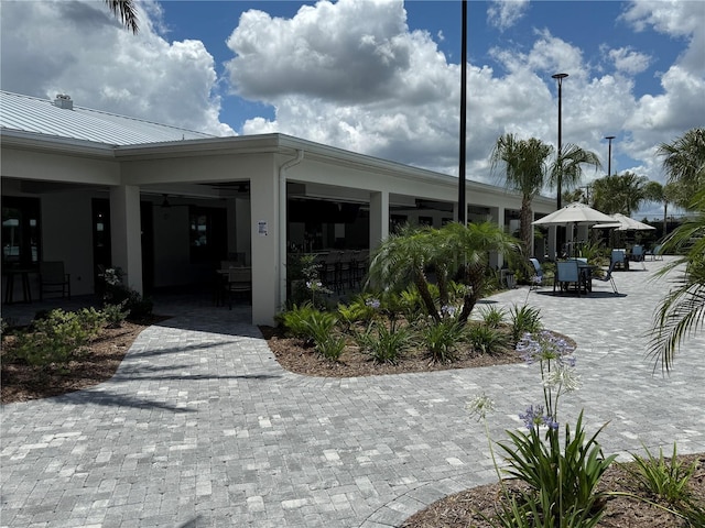 10098 Banyan Breeze Blvd, Land O Lakes, FL 34638 - view of home's exterior with a patio, outdoor dining space, metal roof, and a standing seam roof
