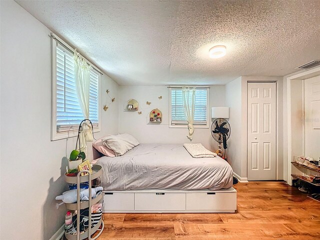 1221 E Hamilton Ave, Tampa, FL 33604 - bedroom with a textured ceiling, wood finished floors, and multiple windows