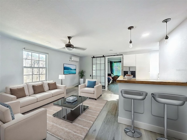 1221 E Hamilton Ave, Tampa, FL 33604 - living room with a barn door, light wood finished floors, a wall mounted air conditioner, ceiling fan, and baseboards