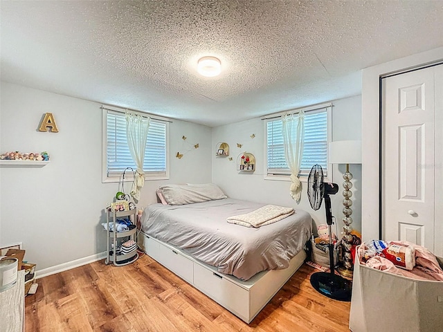 1221 E Hamilton Ave, Tampa, FL 33604 - bedroom with a textured ceiling, light wood-style floors, multiple windows, and baseboards