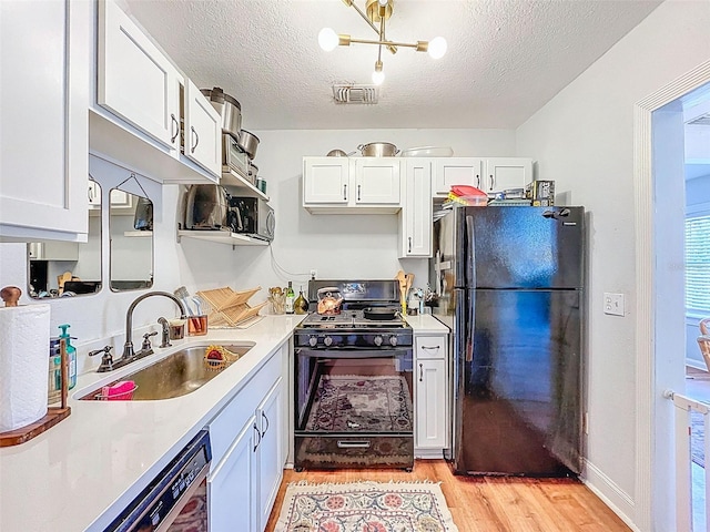 1221 E Hamilton Ave, Tampa, FL 33604 - kitchen with black appliances, a sink, light wood-type flooring, white cabinets, and light countertops