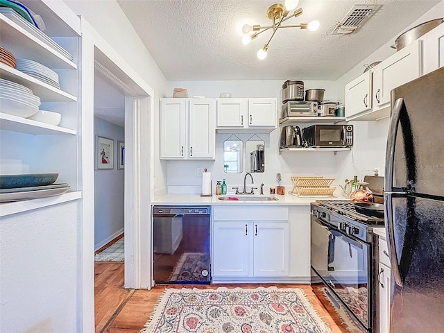 1221 E Hamilton Ave, Tampa, FL 33604 - kitchen with black appliances, a sink, light wood-style floors, white cabinets, and light countertops