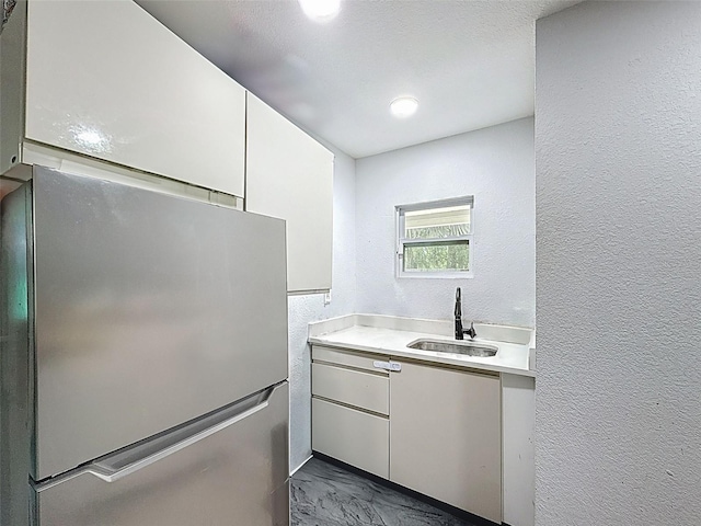 1221 E Hamilton Ave, Tampa, FL 33604 - kitchen with a sink, freestanding refrigerator, light countertops, dark marble finish floors, and a textured wall