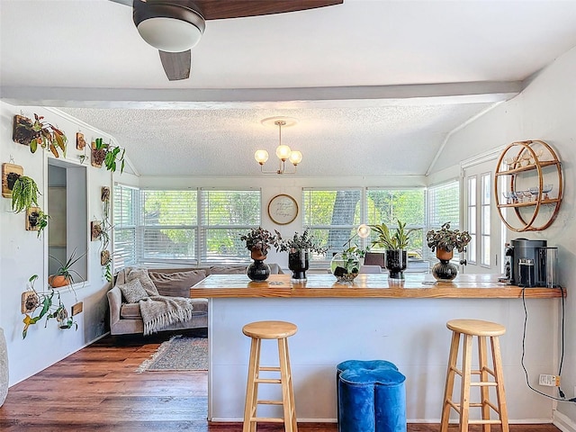 1221 E Hamilton Ave, Tampa, FL 33604 - kitchen featuring wood finished floors, a breakfast bar, a textured ceiling, a chandelier, and a peninsula