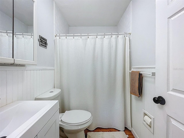 1221 E Hamilton Ave, Tampa, FL 33604 - bathroom featuring toilet, wainscoting, vanity, curtained shower, and wood finished floors