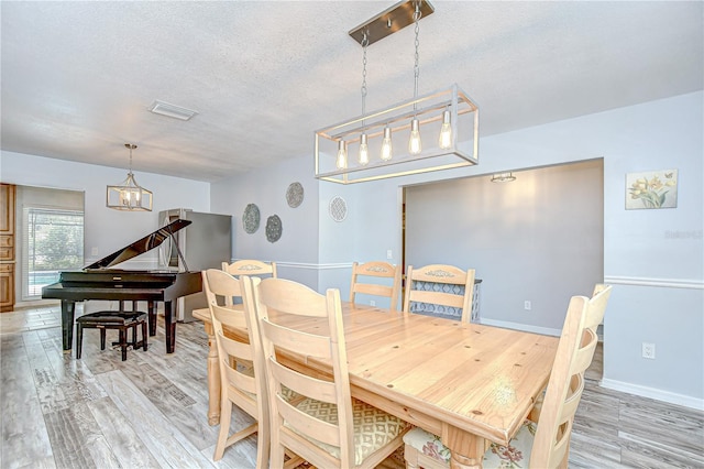 2524 Laurelwood Ln, Valrico, FL 33596 - dining room featuring light wood-style flooring, a textured ceiling, a chandelier, and baseboards