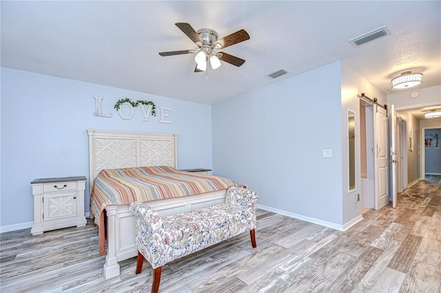 2524 Laurelwood Ln, Valrico, FL 33596 - bedroom with a barn door, light wood finished floors, baseboards, and a ceiling fan
