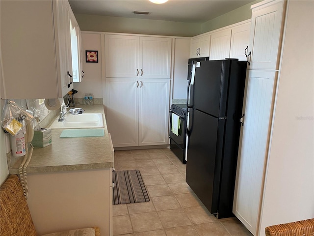 8055 112th St Unit 406, Seminole, FL 33772 - kitchen with black appliances, a sink, white cabinetry, light tile patterned floors, and light countertops