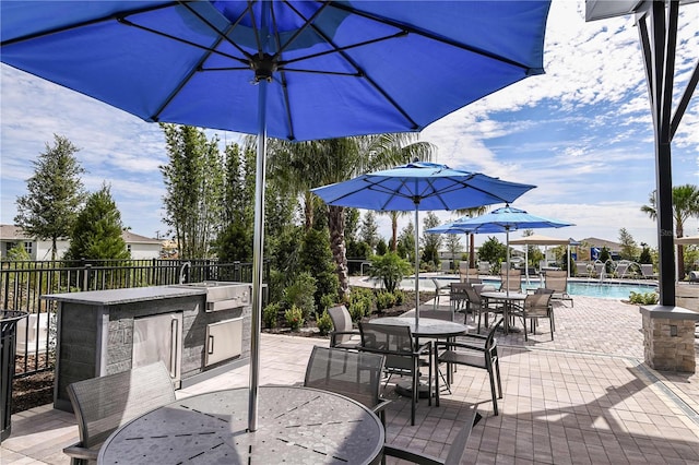view of patio / terrace with outdoor dining space, exterior kitchen, a community pool, a sink, and fence