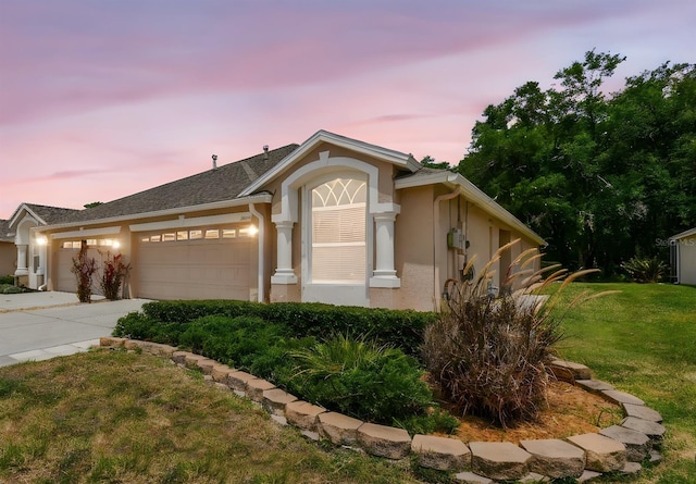 ranch-style house featuring a garage, a front yard, concrete driveway, and stucco siding
