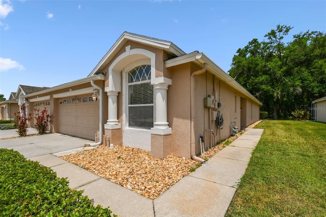view of front of house with stucco siding, a front lawn, concrete driveway, and a garage