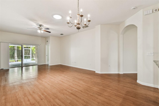 unfurnished room featuring light wood finished floors, baseboards, a chandelier, a ceiling fan, and arched walkways