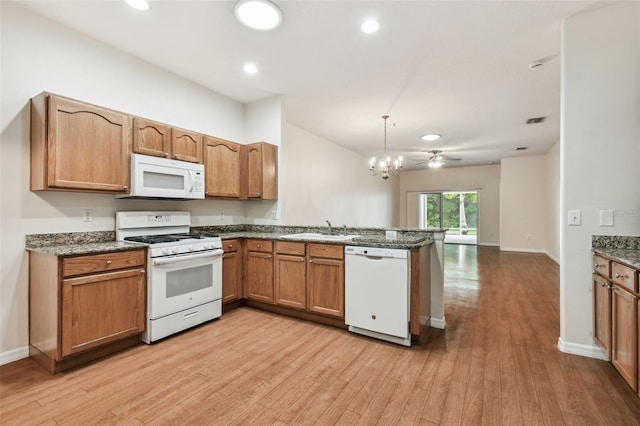 kitchen with white appliances, a peninsula, light wood finished floors, a sink, and a chandelier