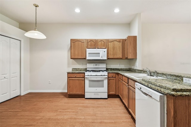 kitchen featuring white appliances, a sink, light wood-type flooring, brown cabinetry, and recessed lighting