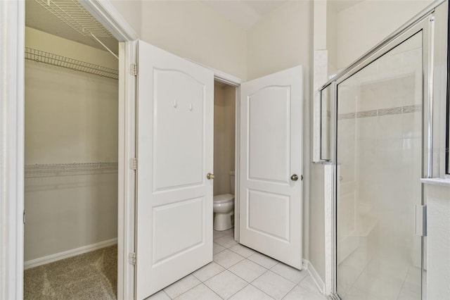 full bath featuring a shower stall, toilet, a spacious closet, and tile patterned floors