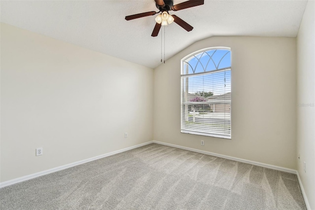 carpeted spare room featuring vaulted ceiling, a ceiling fan, and baseboards