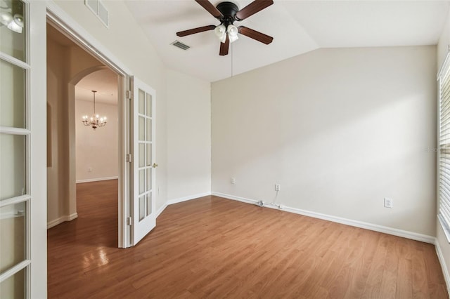 spare room with wood finished floors, a ceiling fan, lofted ceiling, baseboards, and arched walkways