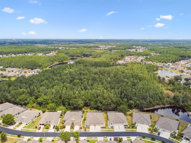 aerial view of property's location featuring a nearby body of water, a heavily wooded area, and nearby suburban area