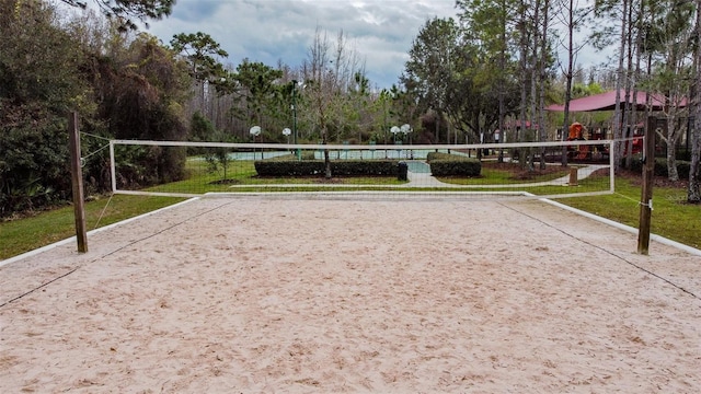 surrounding community with volleyball court and view of wooded area