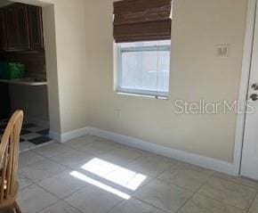 unfurnished dining area with baseboards and tile patterned floors