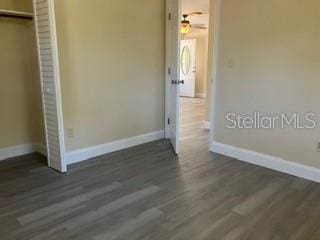 unfurnished bedroom with wood finished floors, baseboards, and a closet