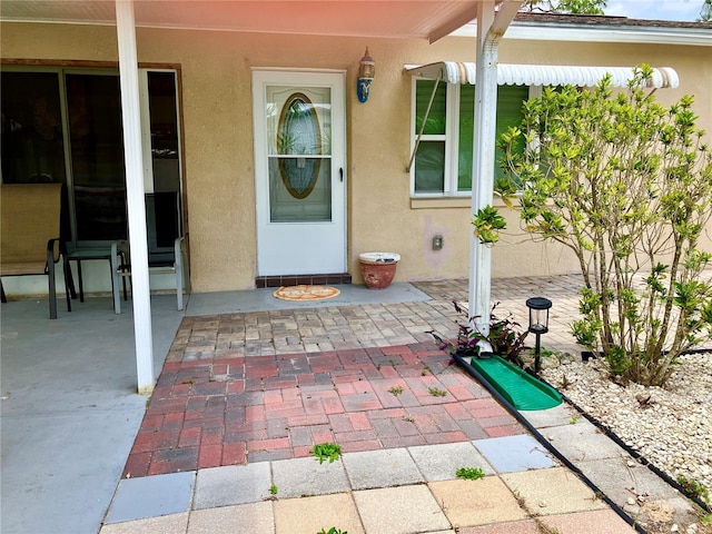 7425 W Maryland Ave W, Hudson, FL 34667 - doorway to property featuring stucco siding and a patio area