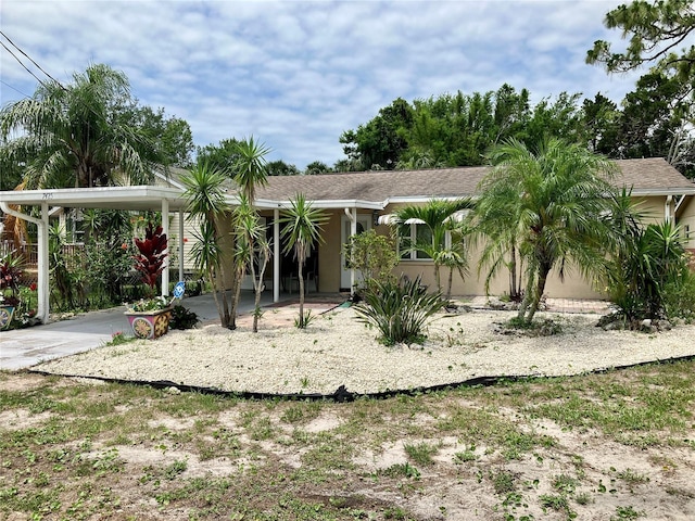 7425 W Maryland Ave W, Hudson, FL 34667 - view of front of house featuring stucco siding, a carport, and driveway