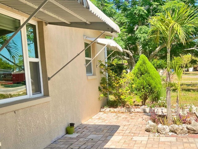 7425 W Maryland Ave W, Hudson, FL 34667 - view of side of property with stucco siding and a patio