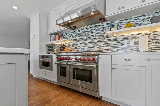 297 1st St W, Tierra Verde, FL 33715 - kitchen with stainless steel appliances, extractor fan, white cabinetry, light countertops, and tasteful backsplash