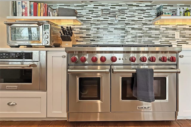 297 1st St W, Tierra Verde, FL 33715 - kitchen view of stainless steel appliances, tasteful backsplash, white cabinets, and wood finished floors
