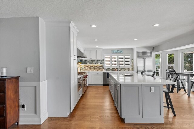 297 1st St W, Tierra Verde, FL 33715 - kitchen featuring appliances with stainless steel finishes, under cabinet range hood, a center island, white cabinetry, and recessed lighting