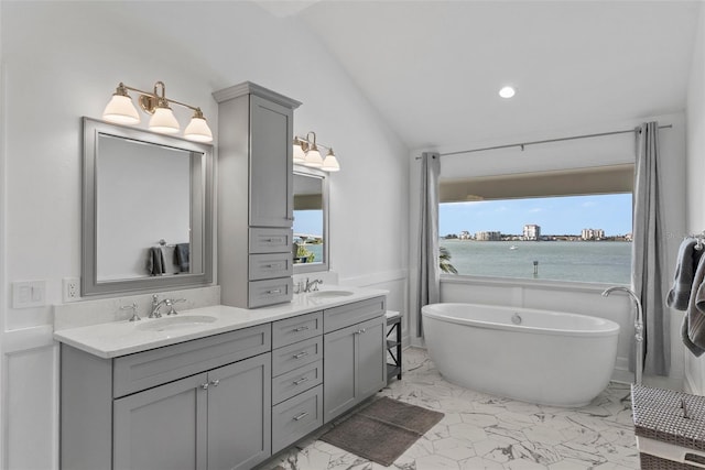 297 1st St W, Tierra Verde, FL 33715 - full bath featuring vaulted ceiling, marble look tile flooring, double vanity, a freestanding bath, and recessed lighting