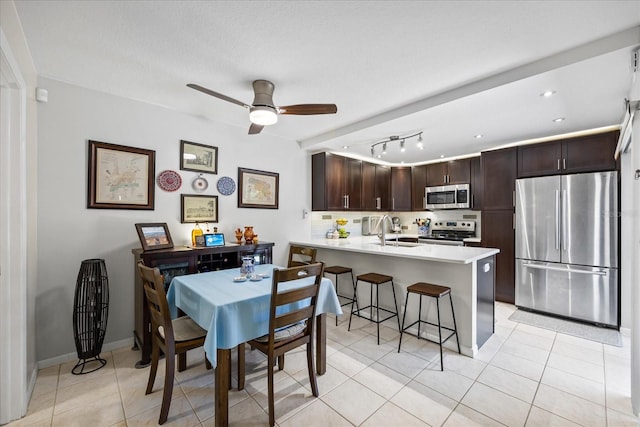 2626 2nd Ct, Palm Harbor, FL 34684 - kitchen featuring appliances with stainless steel finishes, a sink, dark brown cabinetry, a kitchen breakfast bar, and a peninsula